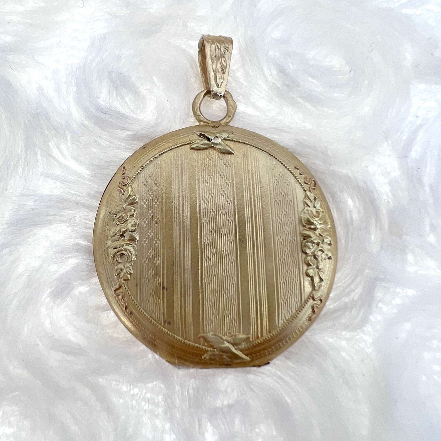 18kt yellow gold round locket pendant, side angle view showing polished smooth surface, weighs approximately 5.85 grams