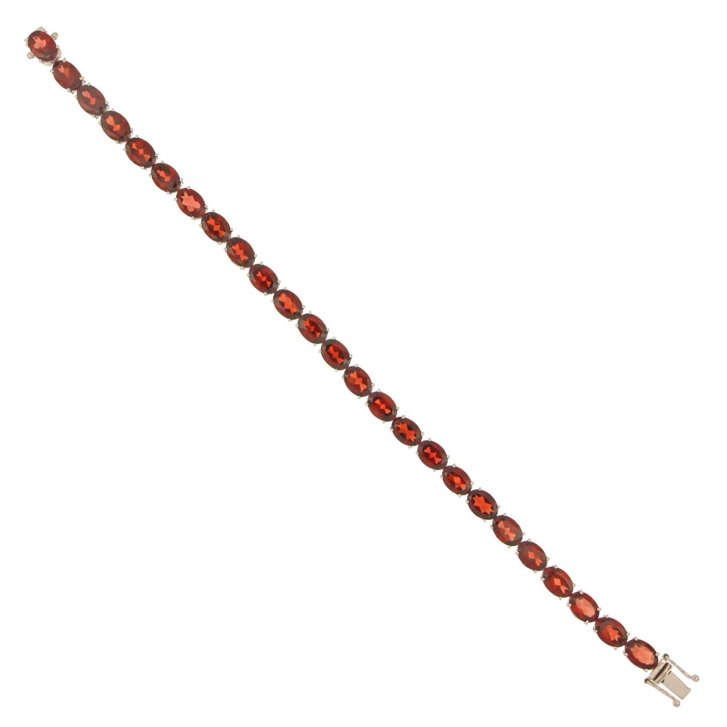 Detailed shot of oval garnet stones arranged on 14kt white gold bracelet with polished finish