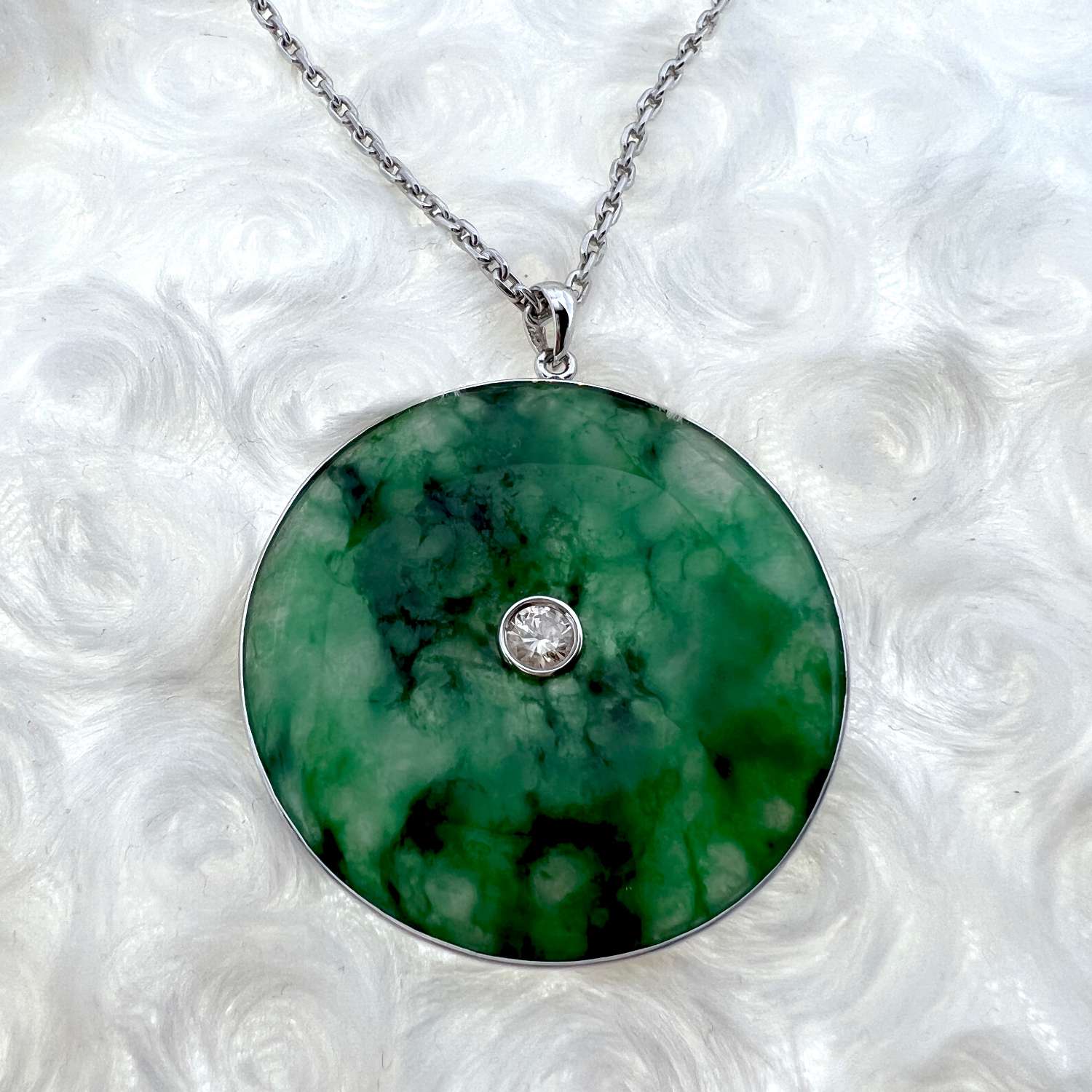 Side angle of 18kt white gold jadeite pendant highlighting 0.65ct round brilliant diamond and smooth jadeite jade disc